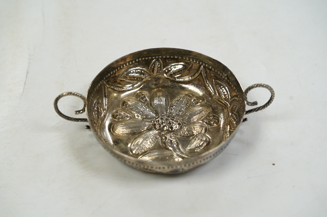 An Edwardian 17th century style Britannia standard silver porringer, by Maurice Freeman, London, circa 1905, 12cm, over handles. Condition - fair